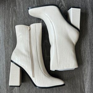 White ankle croc style boots with black trim and zipper
